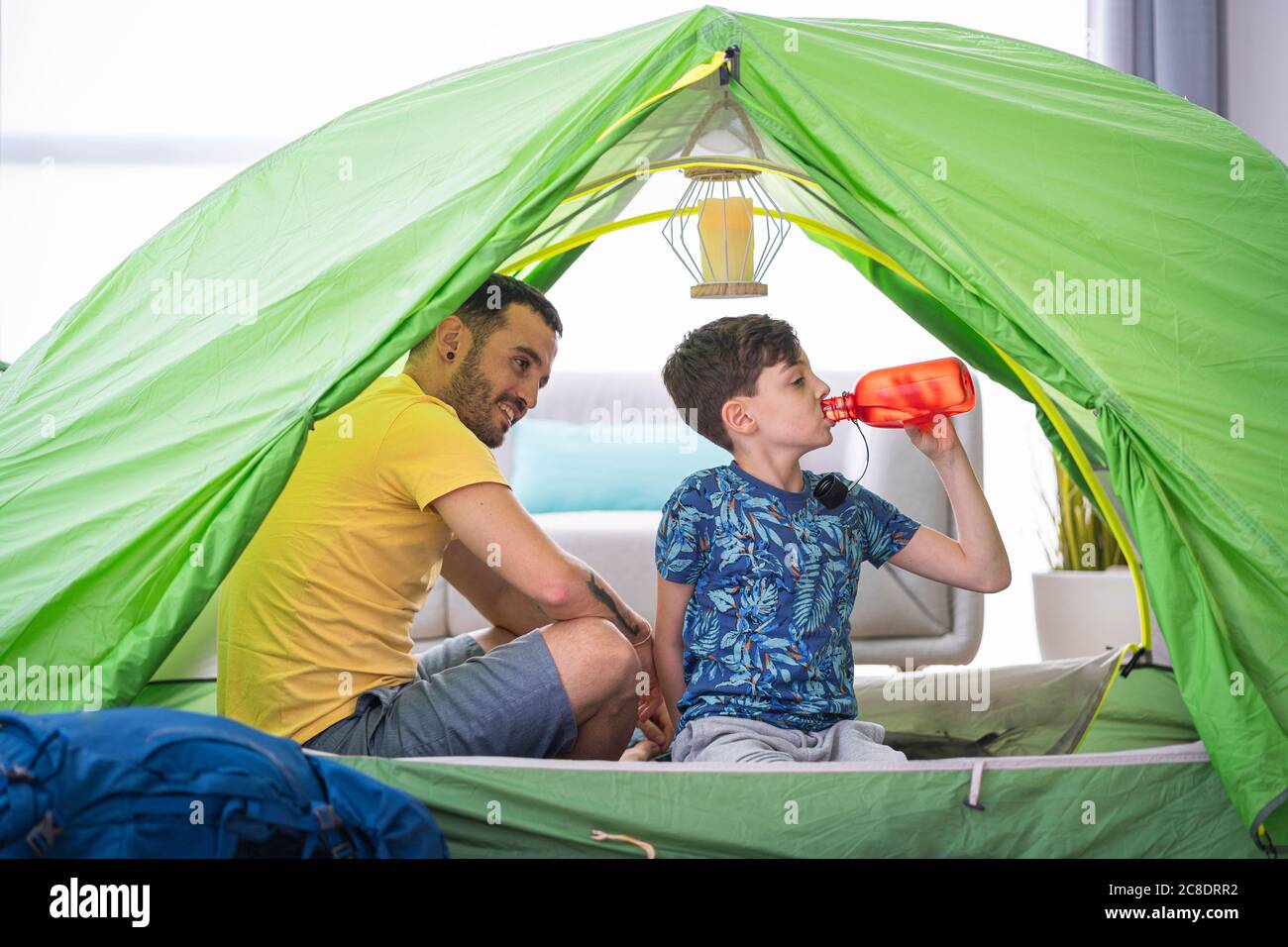 Vater und Sohn im Zelt zu Hause, Junge trinkt aus der Flasche Stockfoto
