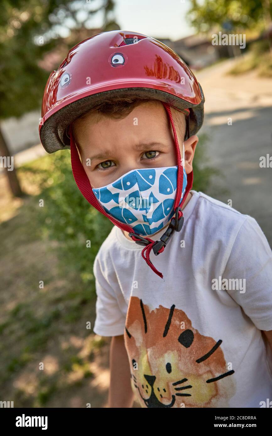 Nahaufnahme eines Jungen mit Maske und rotem Helm, der im Freien steht Stockfoto