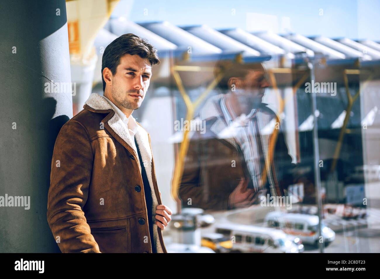 Durchdachter Geschäftsmann, der am Abflugbereich des Flughafens am Fenster steht Stockfoto