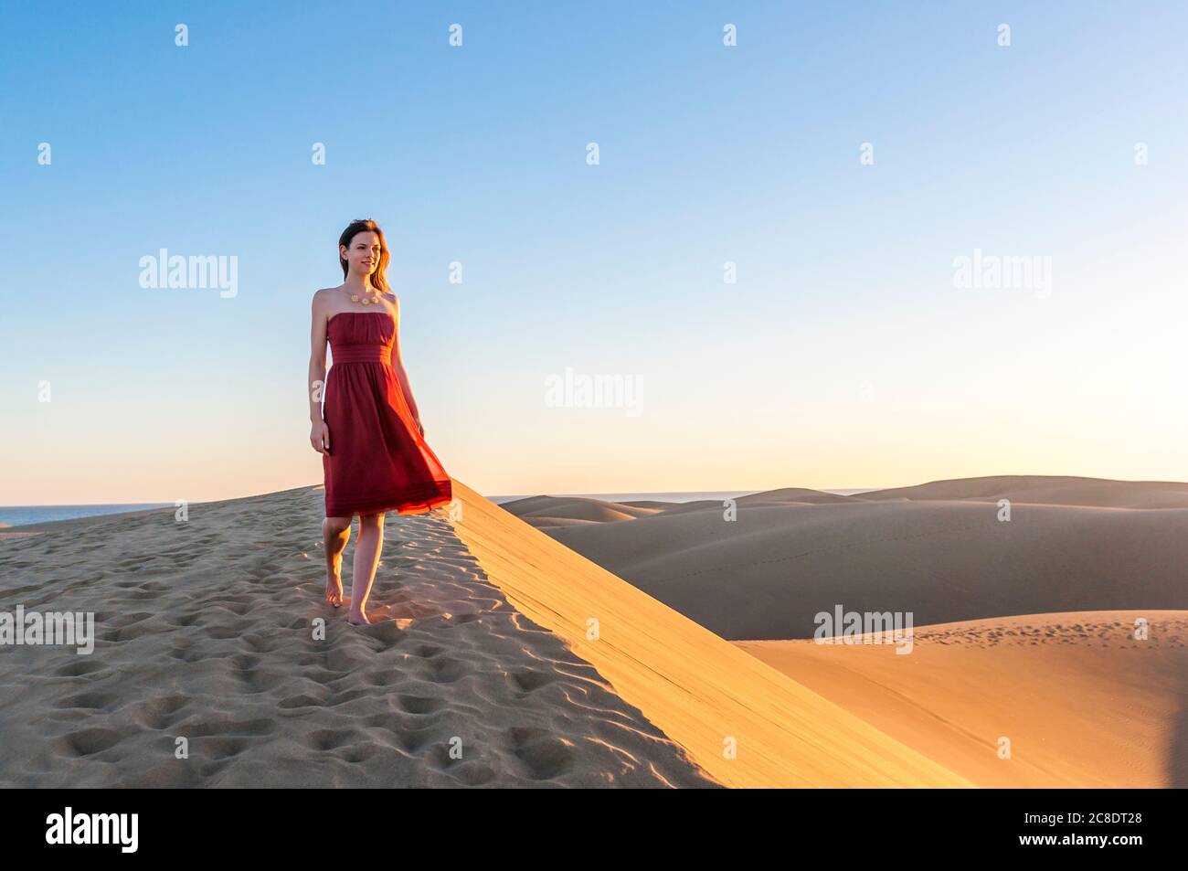 Frau in rotem Kleid beim Sonnenuntergang in den Dünen, Gran Canaria, Spanien Stockfoto