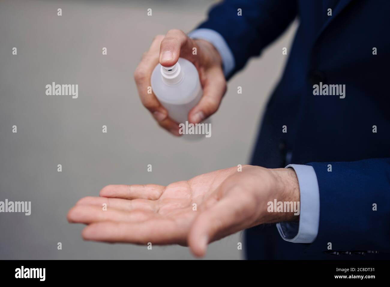 Nahaufnahme eines Geschäftsmannes, der seine Hände mit einem Spray desinfiziert Stockfoto