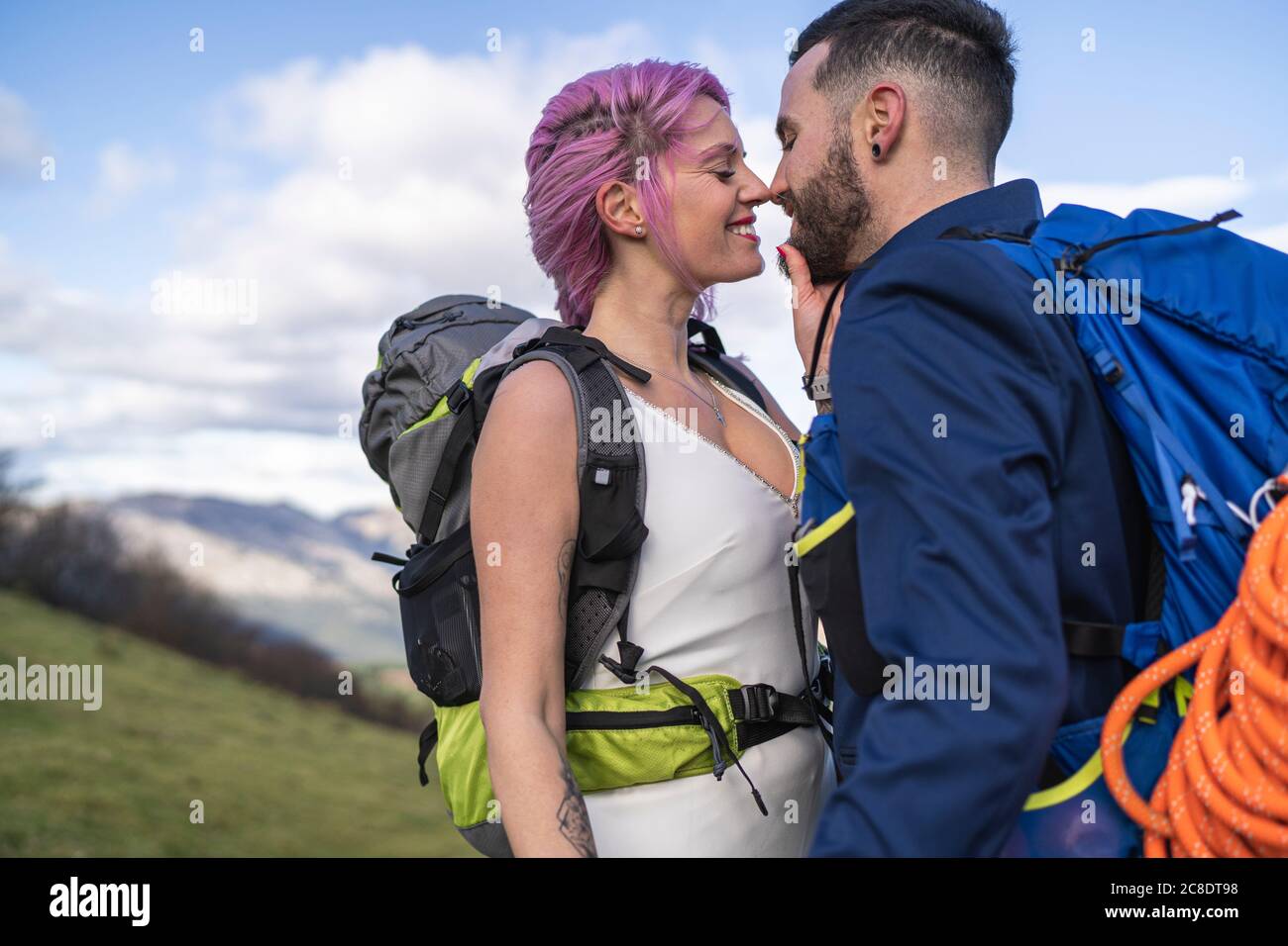 Küssendes Brautpaar mit Kletterrucksäcken am Urkiola Berg, Spanien Stockfoto