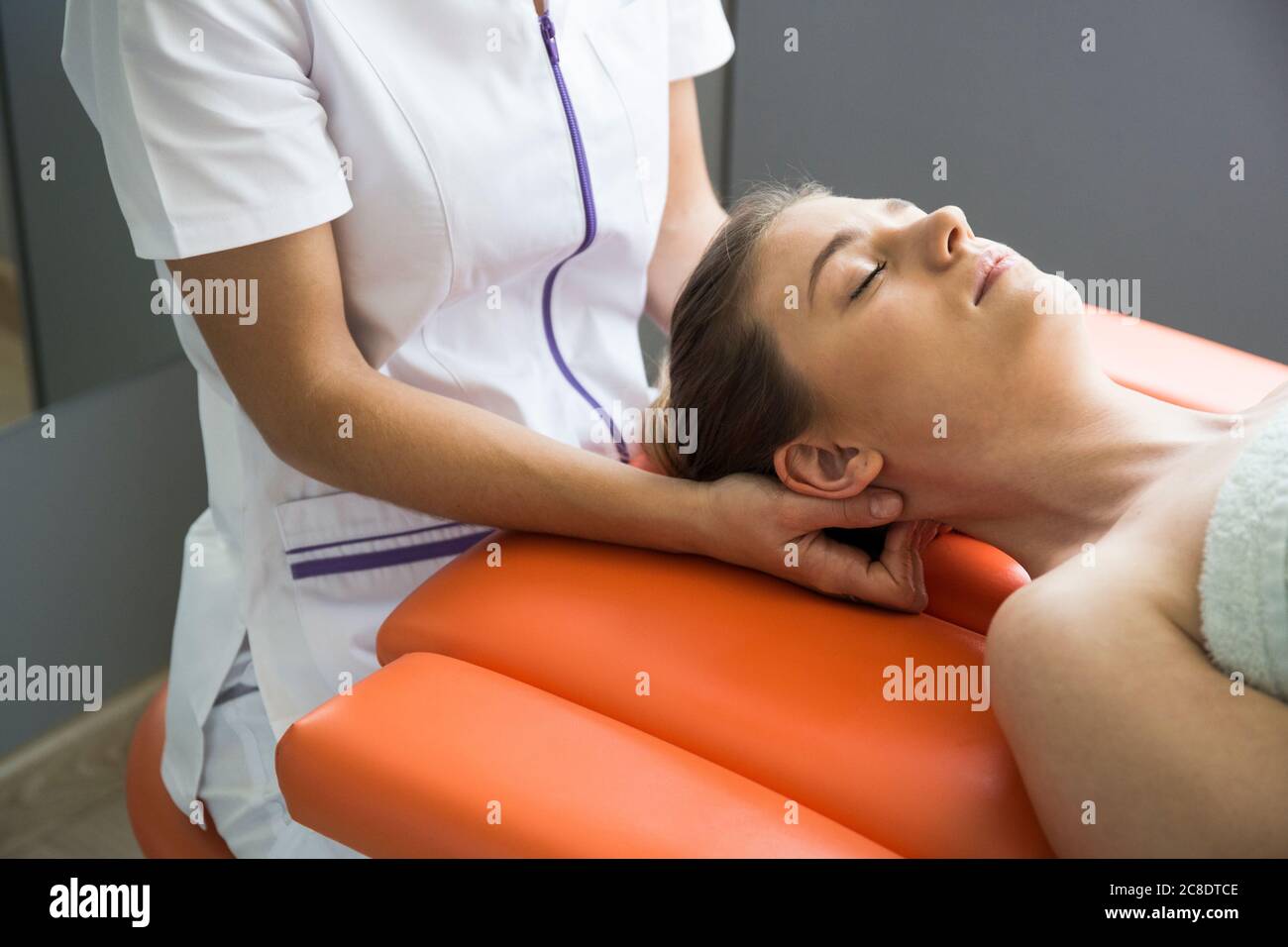 Hände einer weiblichen Physiotherapeutin massieren den Hals einer Frau Stockfoto