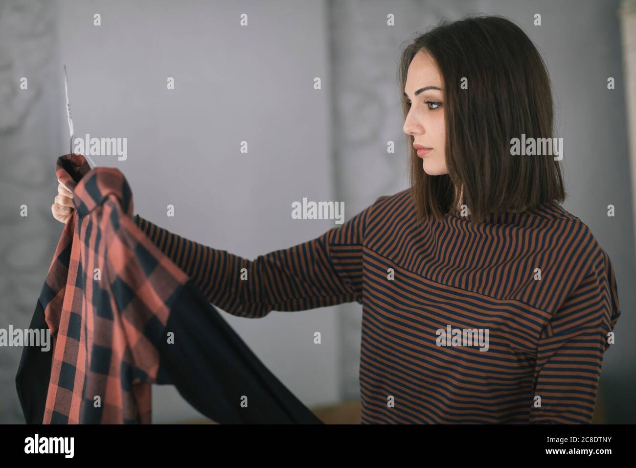 Junge Frau, die oben untersucht, während sie im Bekleidungsdesignstudio steht Stockfoto