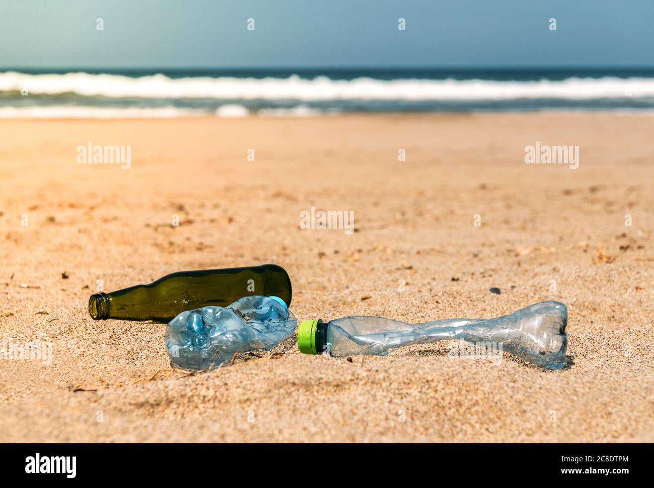 Glas- und Plastikflaschen liegen auf Strandsand Stockfoto