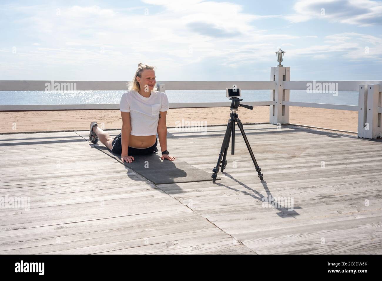 Junge sportliche Frau beim Training und Videoaufnahme am Strand Stockfoto