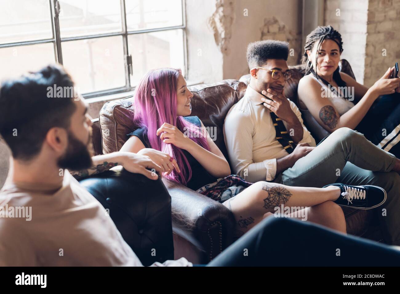 Gruppe von Freunden sitzen auf dem Sofa in einem Loft Stockfoto