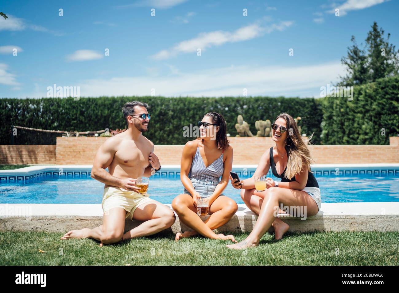 Freunde während der Poolparty mit Bier toasten Stockfoto