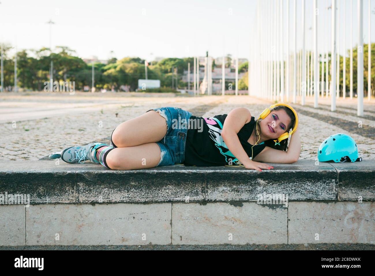 Teenager-Mädchen mit Down-Syndrom tragen 8s bunte Make-up und Musik hören mit gelben Kopfhörern Stockfoto