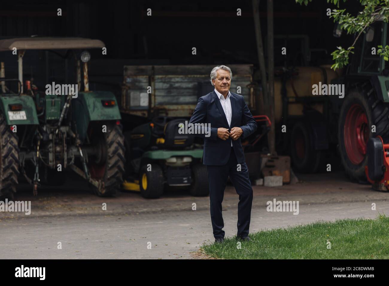 Senior Geschäftsmann auf einem Bauernhof mit Traktor in Scheune Stockfoto