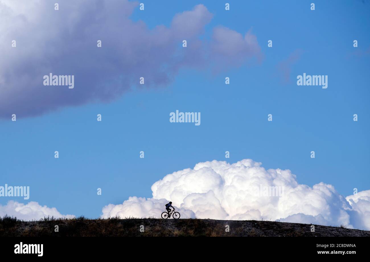 Silhouette Radfahrer Fahrrad fahren auf dem Feld gegen bewölkten blauen Himmel Stockfoto
