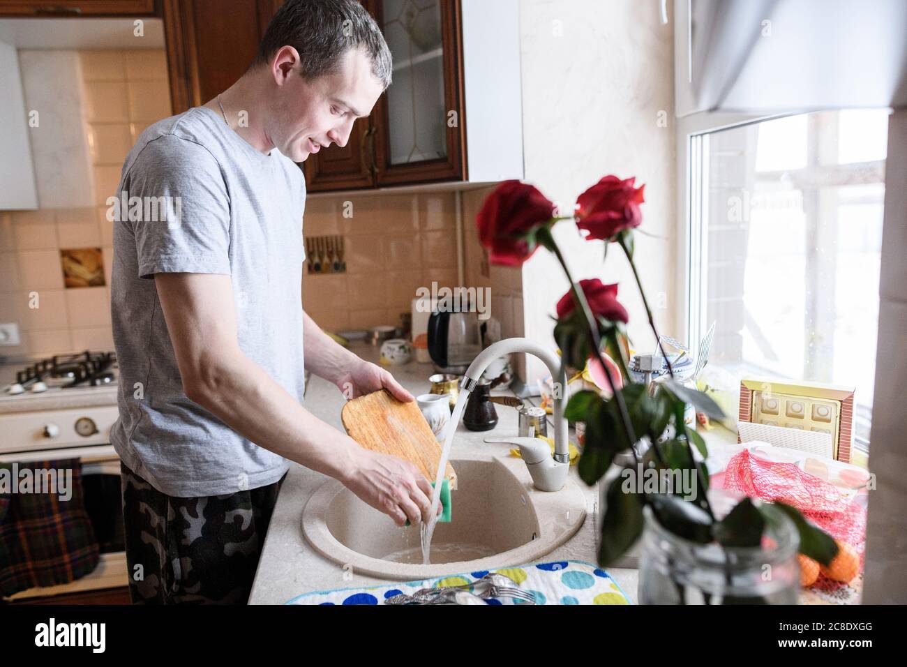 Mann für mittleren Erwachsenen, der Schneidebrett im Küchenwaschbecken wascht Zu Hause Stockfoto