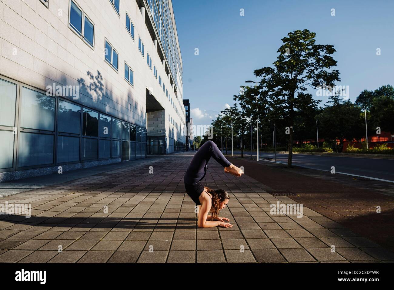 Junge Frau, die Yoga auf dem Bürgersteig in der Stadt bei Sonnenschein Tag Stockfoto
