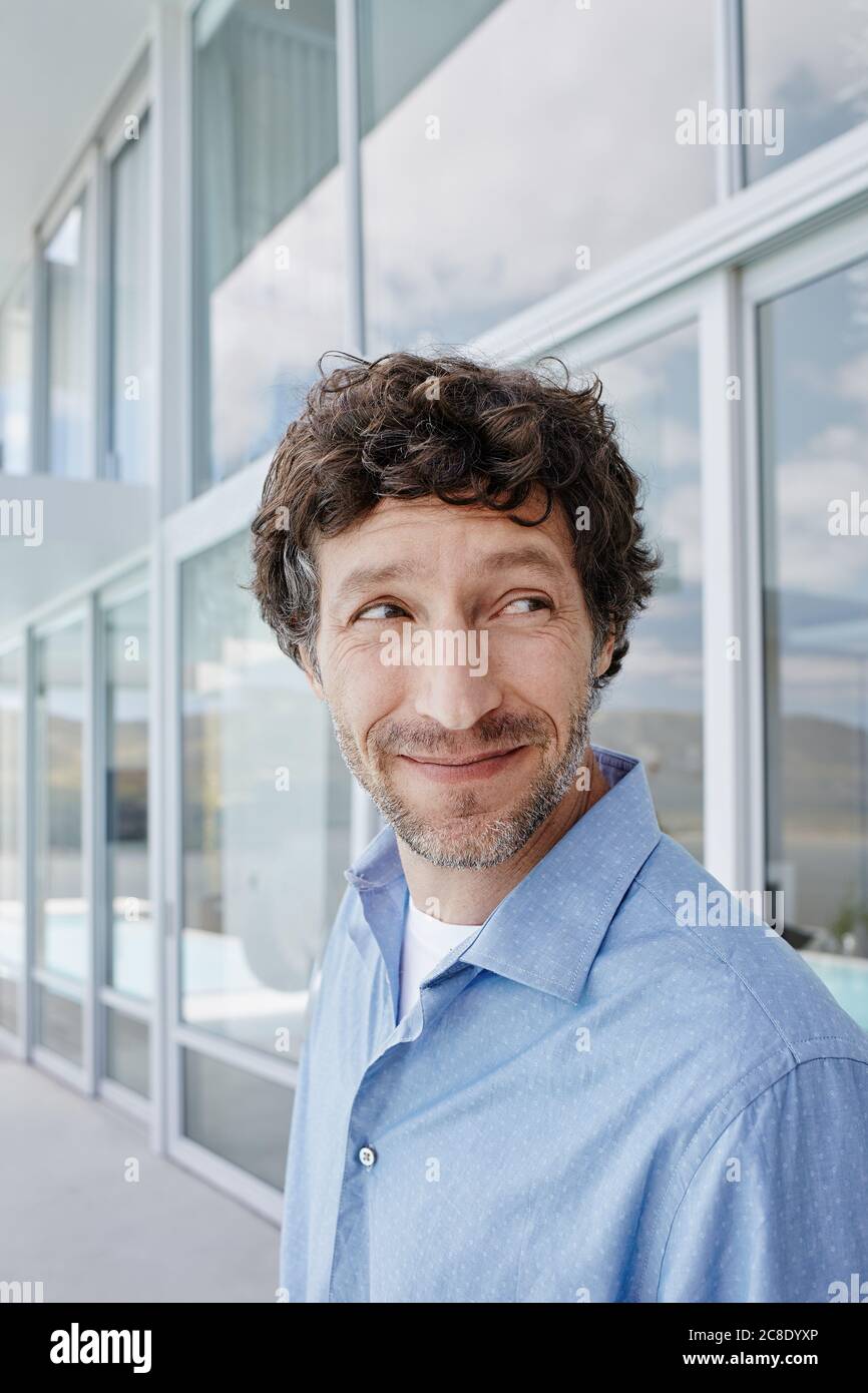 Porträt eines lächelnden Mannes vor einem Haus, der seitwärts schaut Stockfoto