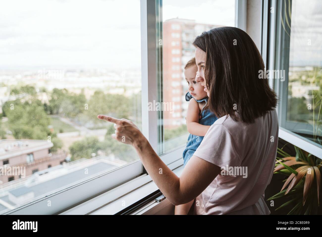Mutter mit Baby Mädchen zu Hause Blick am Fenster Stockfoto
