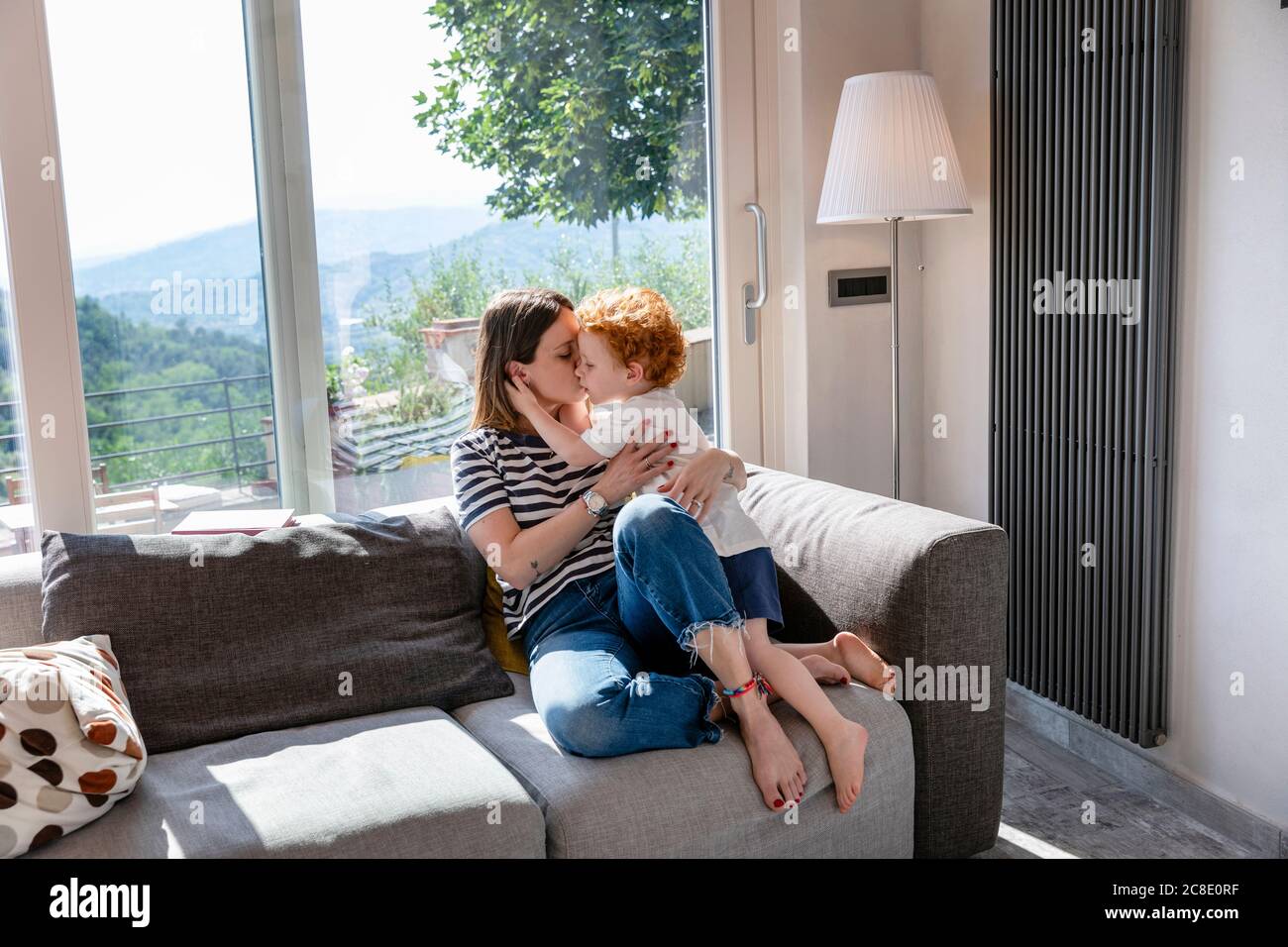 Mutter küsst niedlichen Sohn während sitzen auf Sofa im Leben Zimmer zu Hause Stockfoto