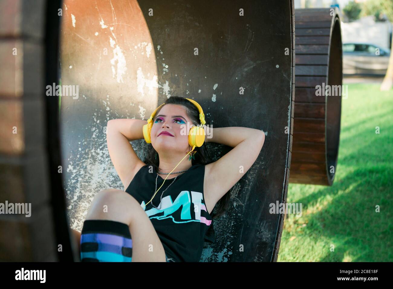 Teenager-Mädchen mit Down-Syndrom tragen 8s bunte Make-up und Musik hören mit gelben Kopfhörern Stockfoto