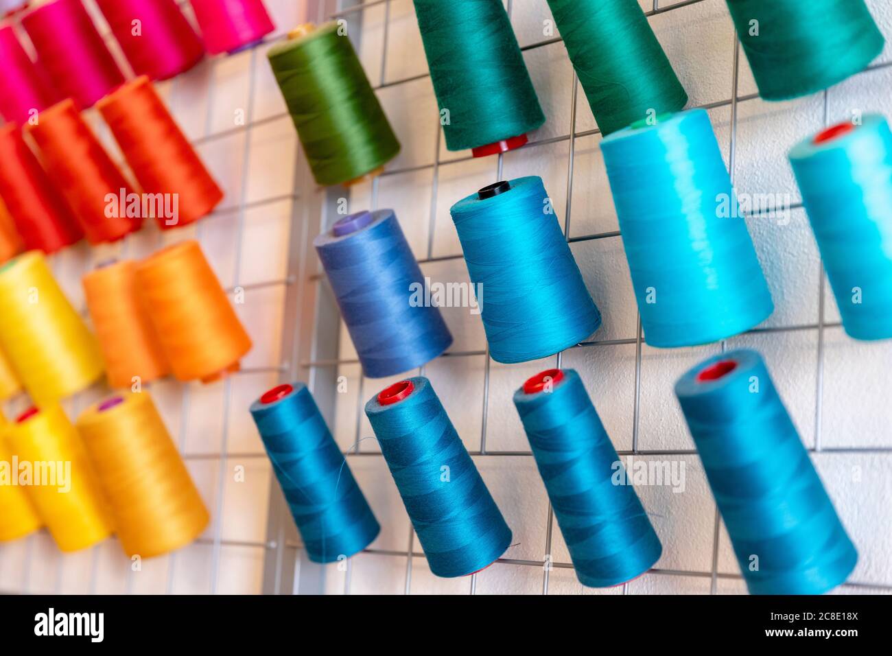 Nahaufnahme von bunten Fadenspulen auf dem Rack im Designstudio Stockfoto