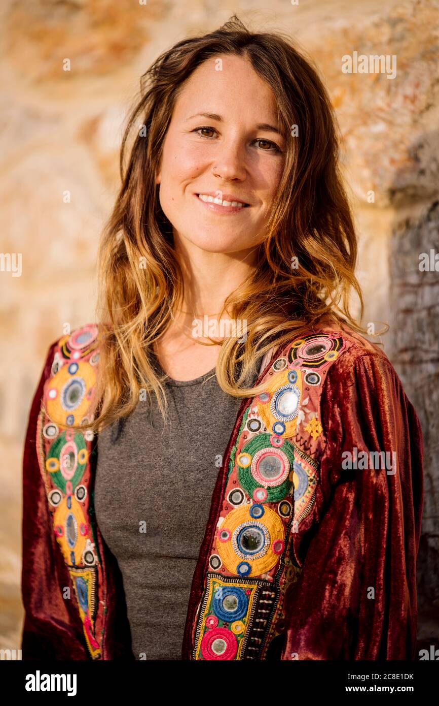 Nahaufnahme einer selbstbewussten Frau, die eine Jacke an der Steinwand trägt Stockfoto
