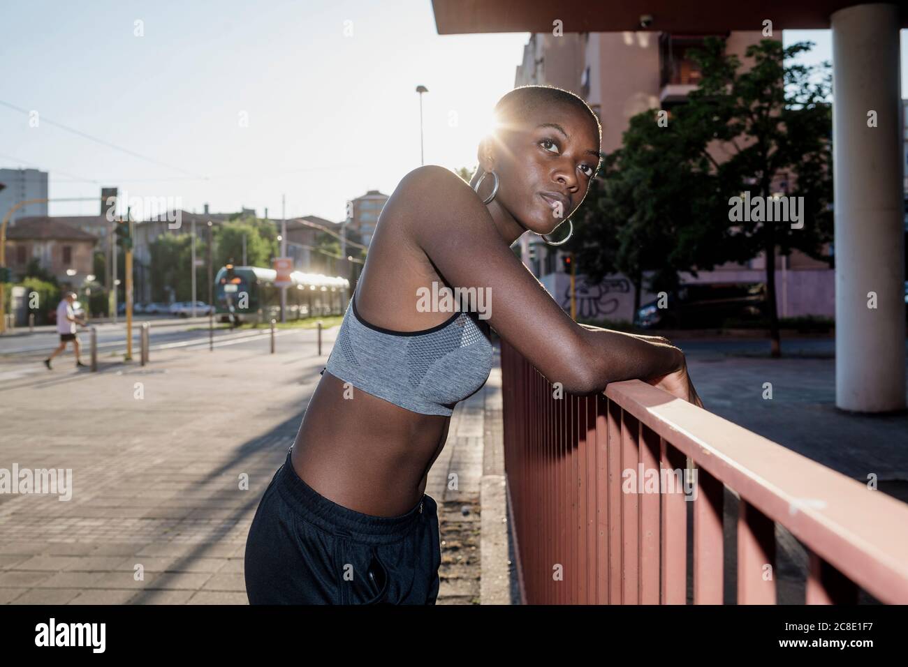 Junge Frau mit kurzen Haaren, die beim Stehen wegschaut Geländer in der Stadt Stockfoto