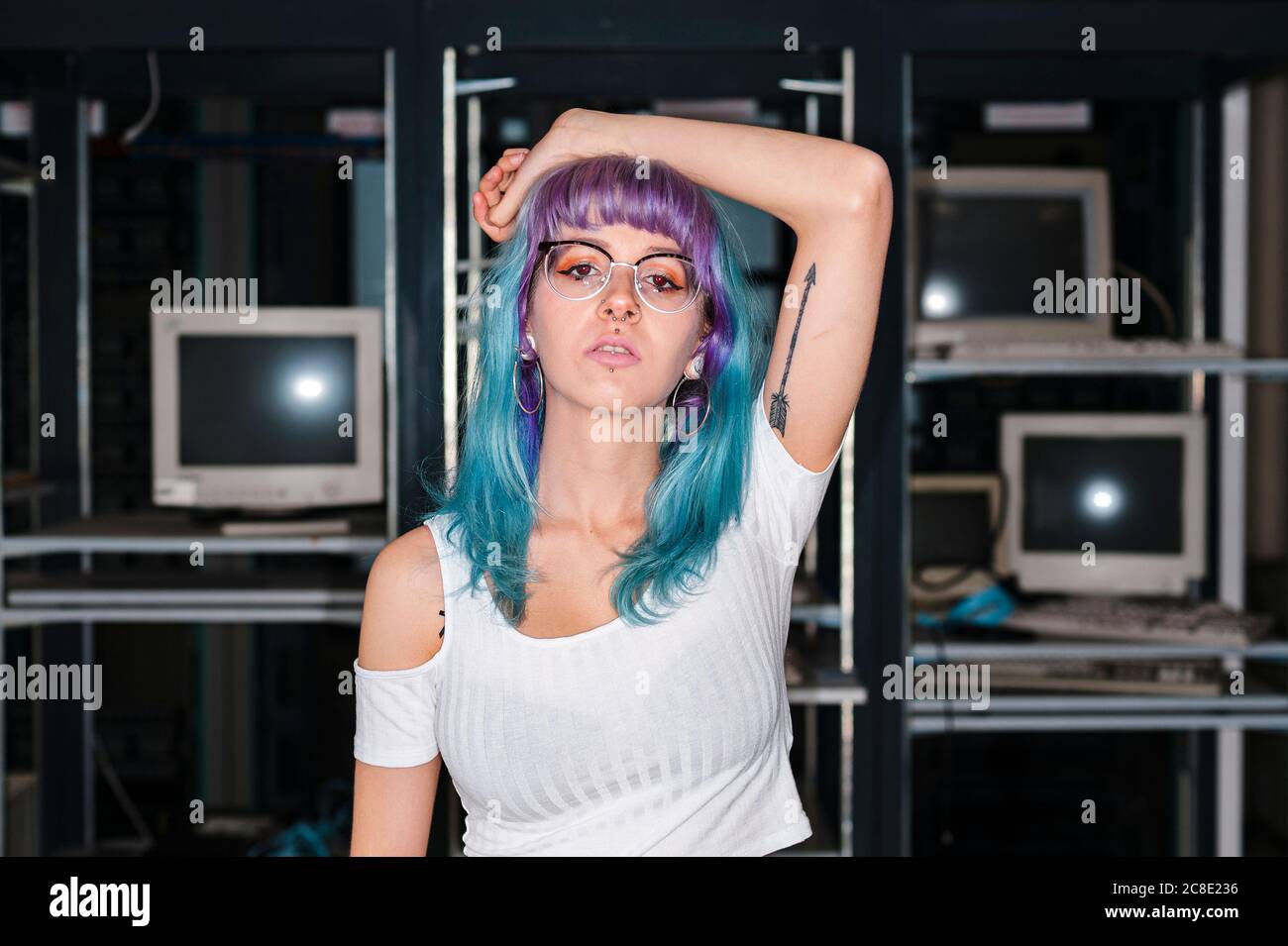 Trendy blauhaarige weibliche Gamer stehen mit Arm angehoben Zu Hause Stockfoto