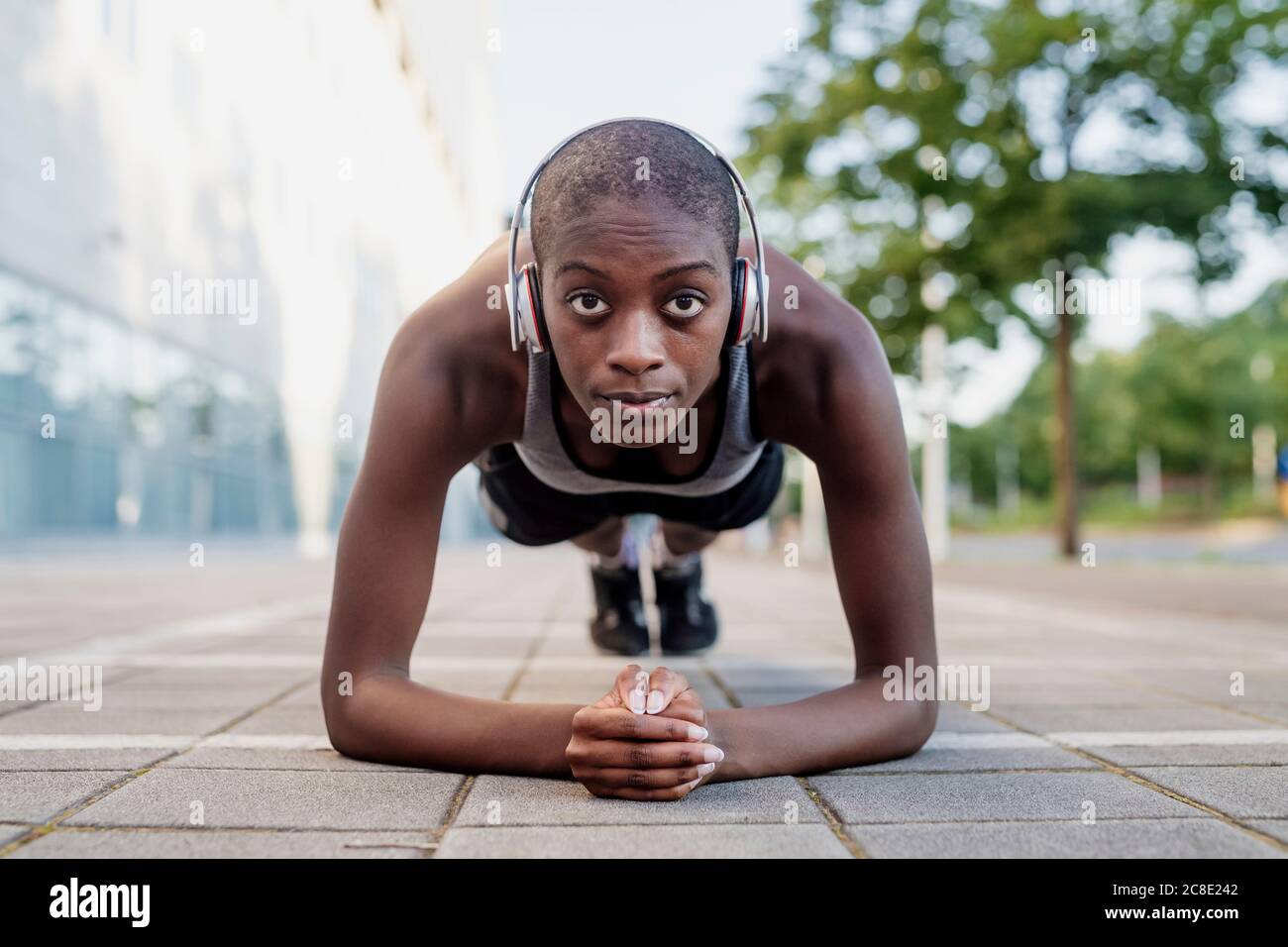 Selbstbewusste Frau mit rasierten Kopf Musik hören, während dabei Planken Auf Fußweg Stockfoto