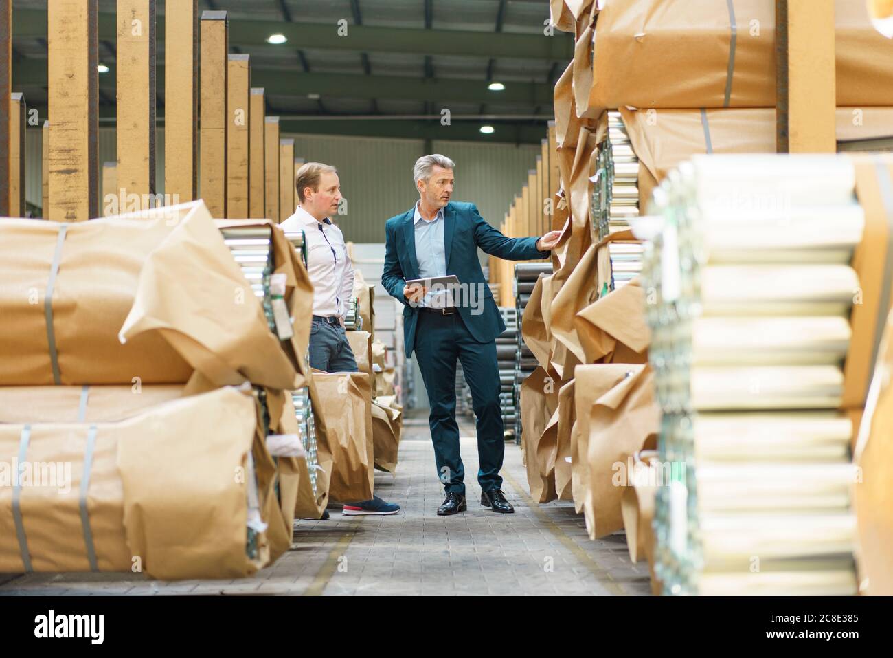 Zwei Geschäftsleute in einem Fabriklager mit Stahlrohren Stockfoto