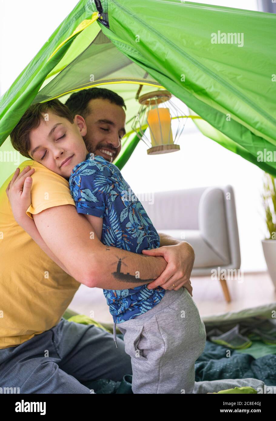 Vater umarmt seinen Sohn im Zelt zu Hause Stockfoto