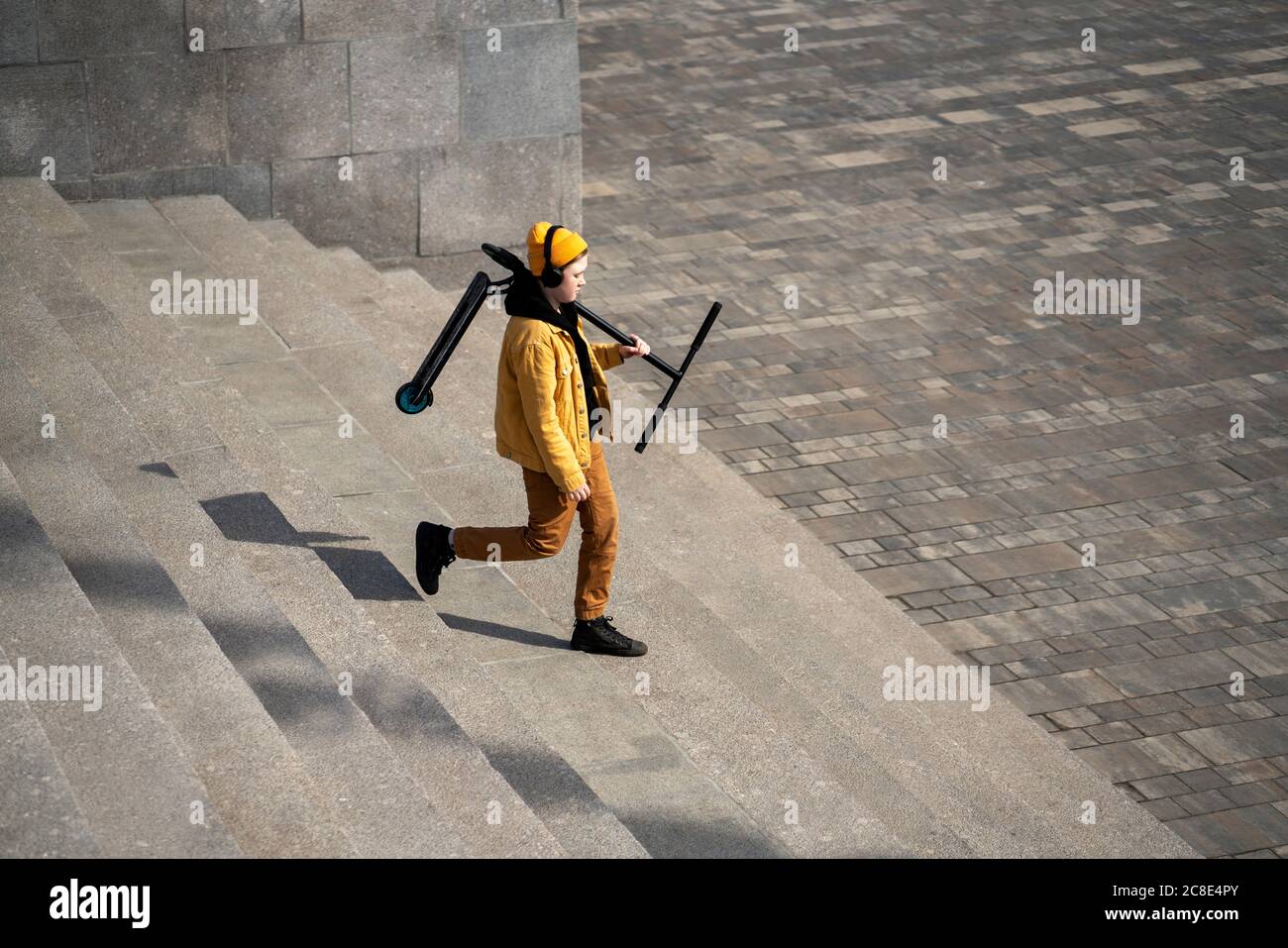 Junge trägt Push-Roller beim Bewegen nach unten auf Stufen Stockfoto