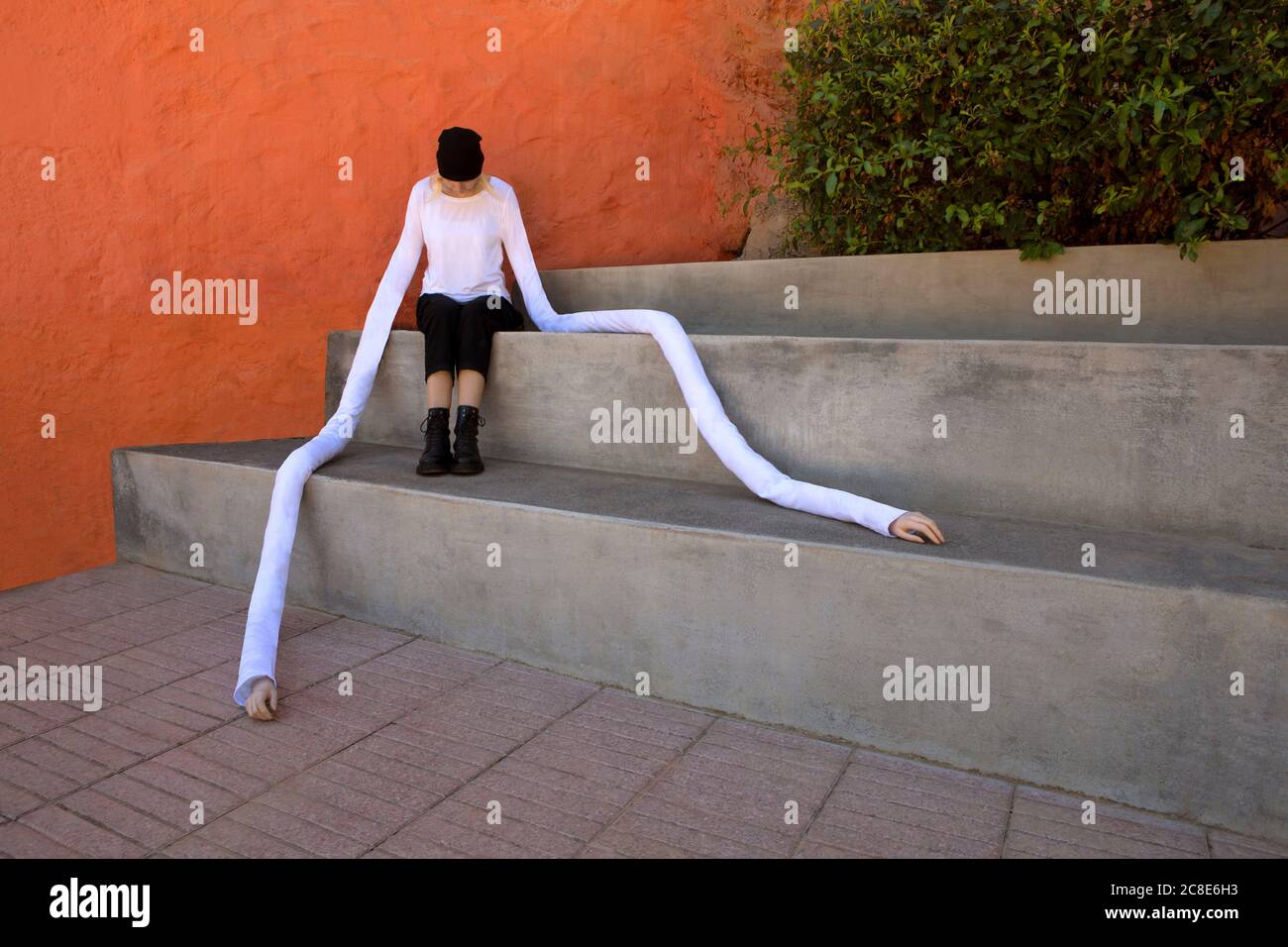 Frau mit langen künstlichen Händen auf Betonstufen sitzen Stockfoto