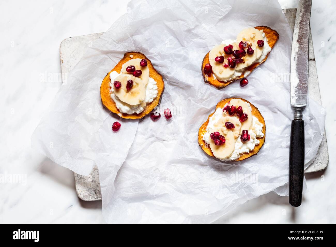 Geröstete Kartoffelscheiben mit Quark, Banane und Granatapfelkernen Stockfoto