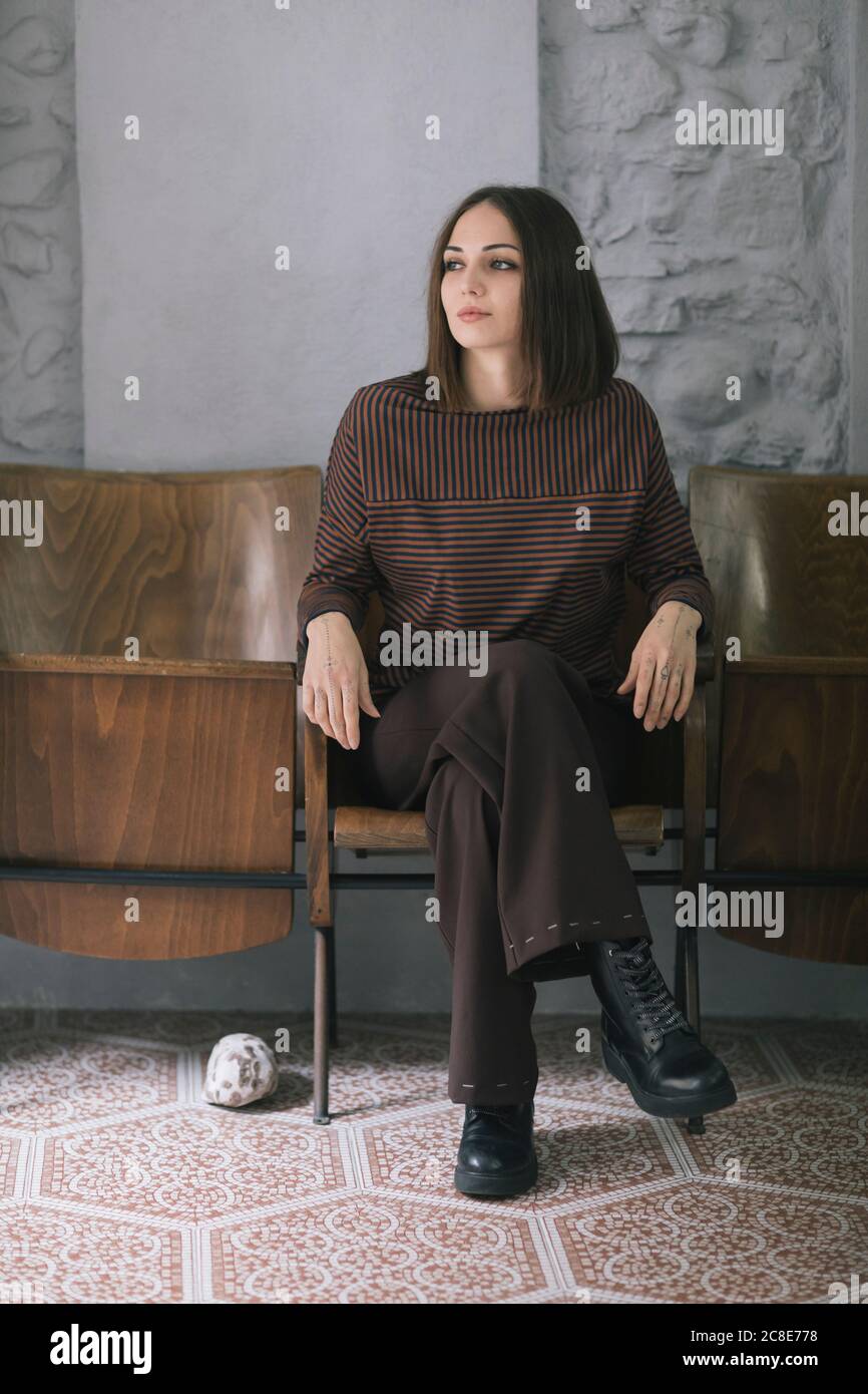 Nachdenklich schöne Frau sitzt auf einem Stuhl in Kleidung Design Studio Stockfoto