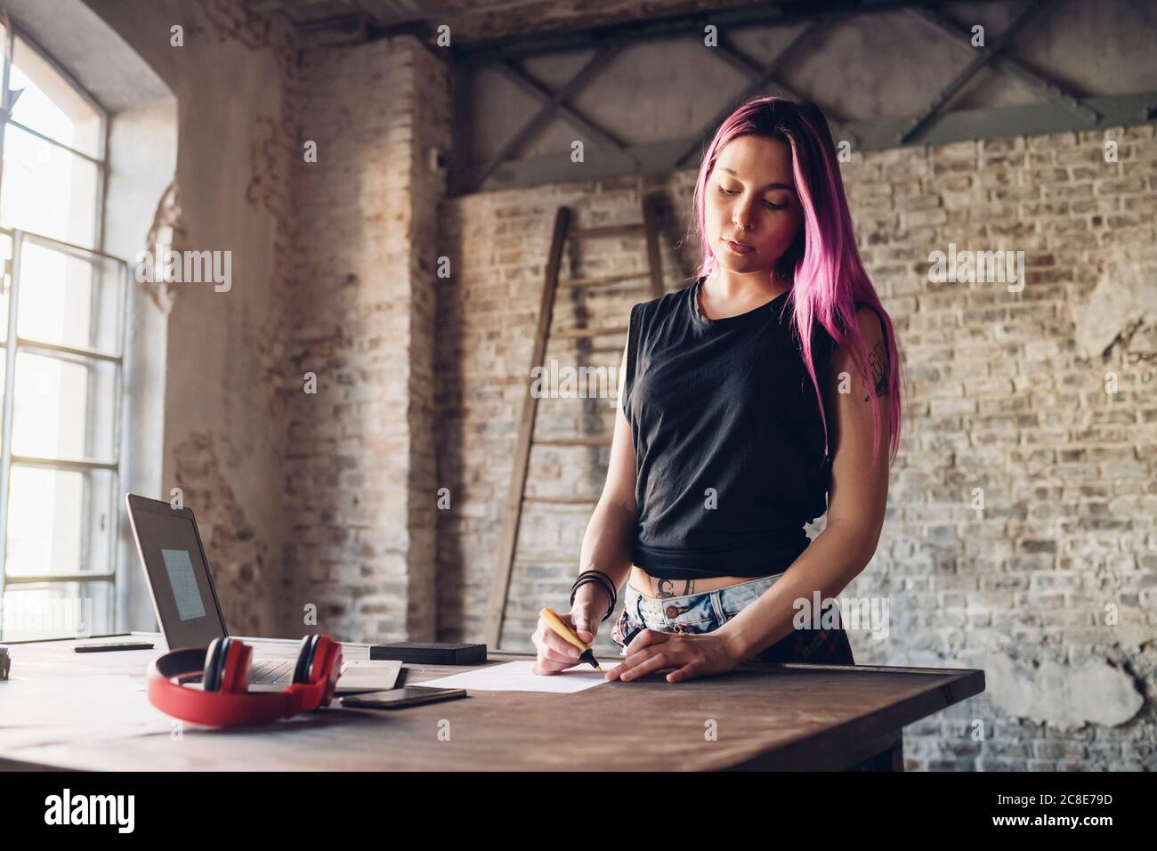 Kreative Geschäftsfrau mit rosa Haaren am Tisch im Loft arbeiten Büro Stockfoto