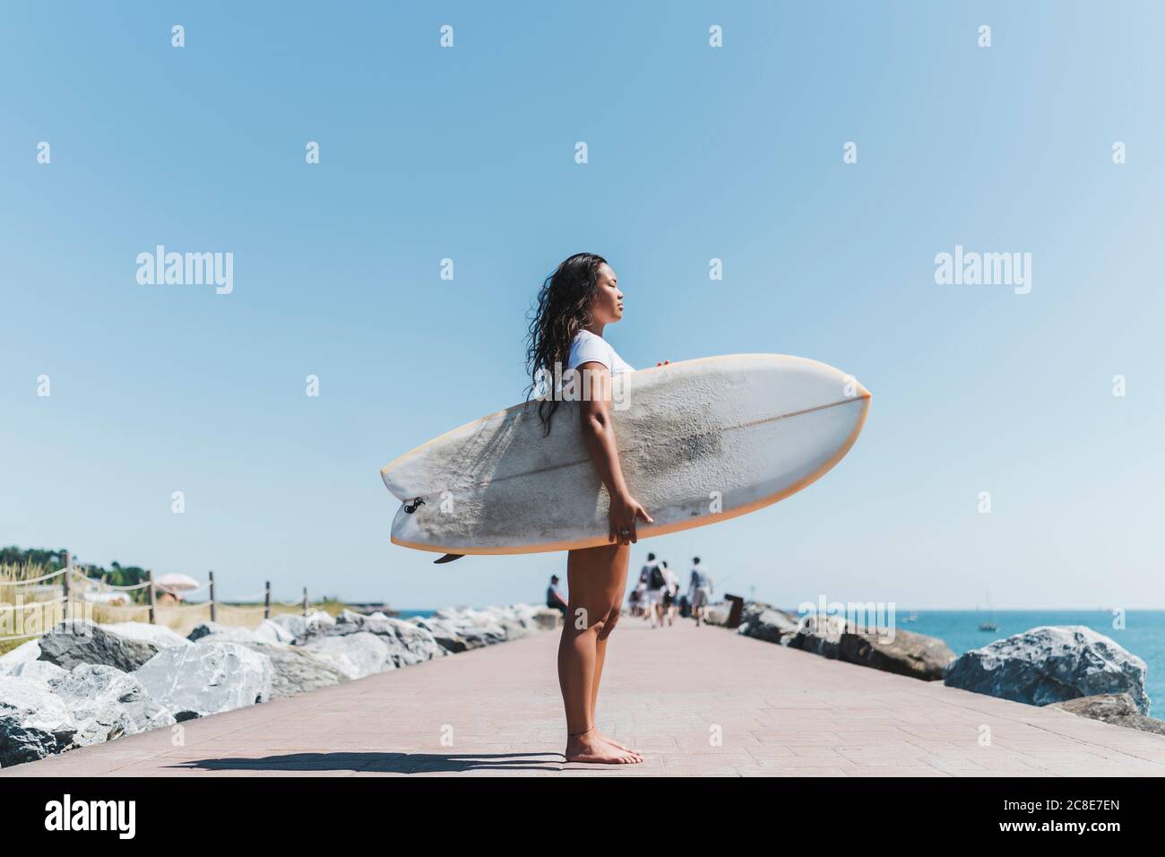 Weibliche Surferin mit Surfbrett im Freien Stockfoto