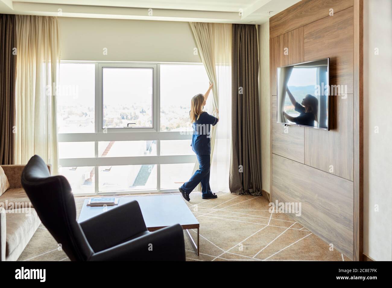 Zimmermädchen öffnete die Fenstervorhänge im Hotelzimmer Stockfoto