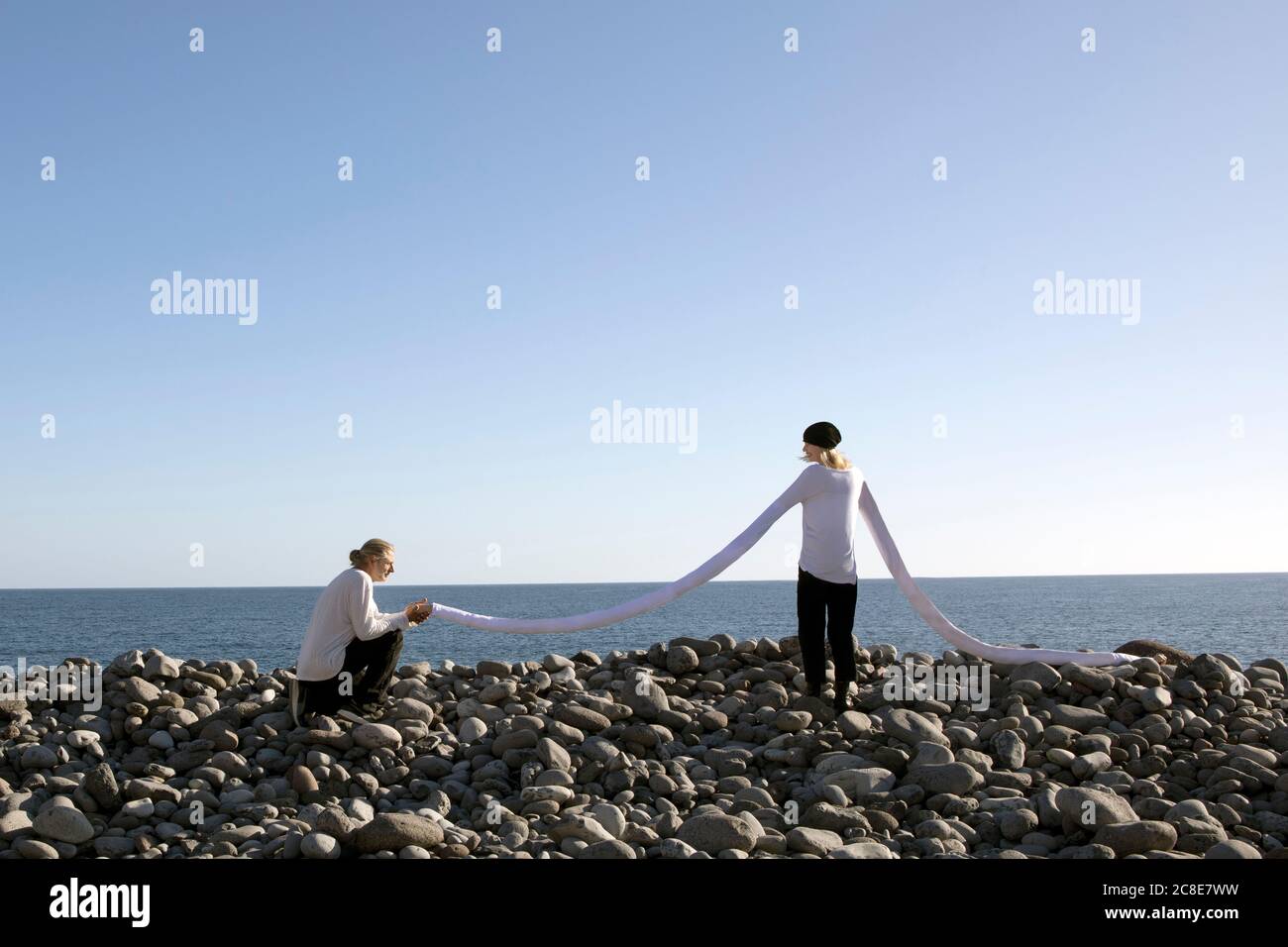 Mann schlägt vor, während Frau lange künstliche Hand am Strand Gegen klaren Himmel Stockfoto
