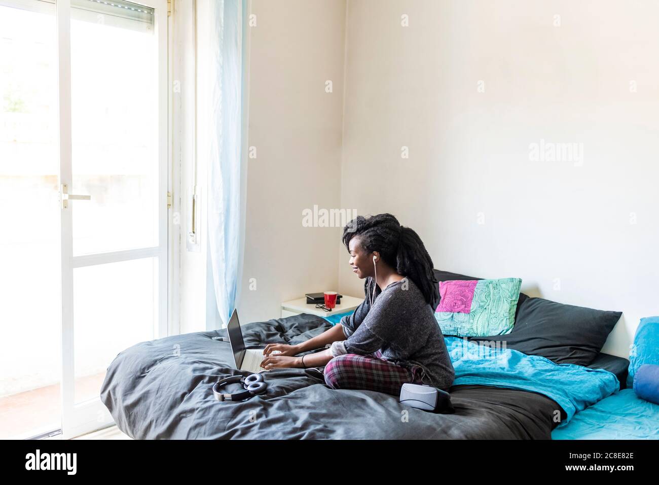 Junge Frau mit Laptop am Bett zu Hause Stockfoto