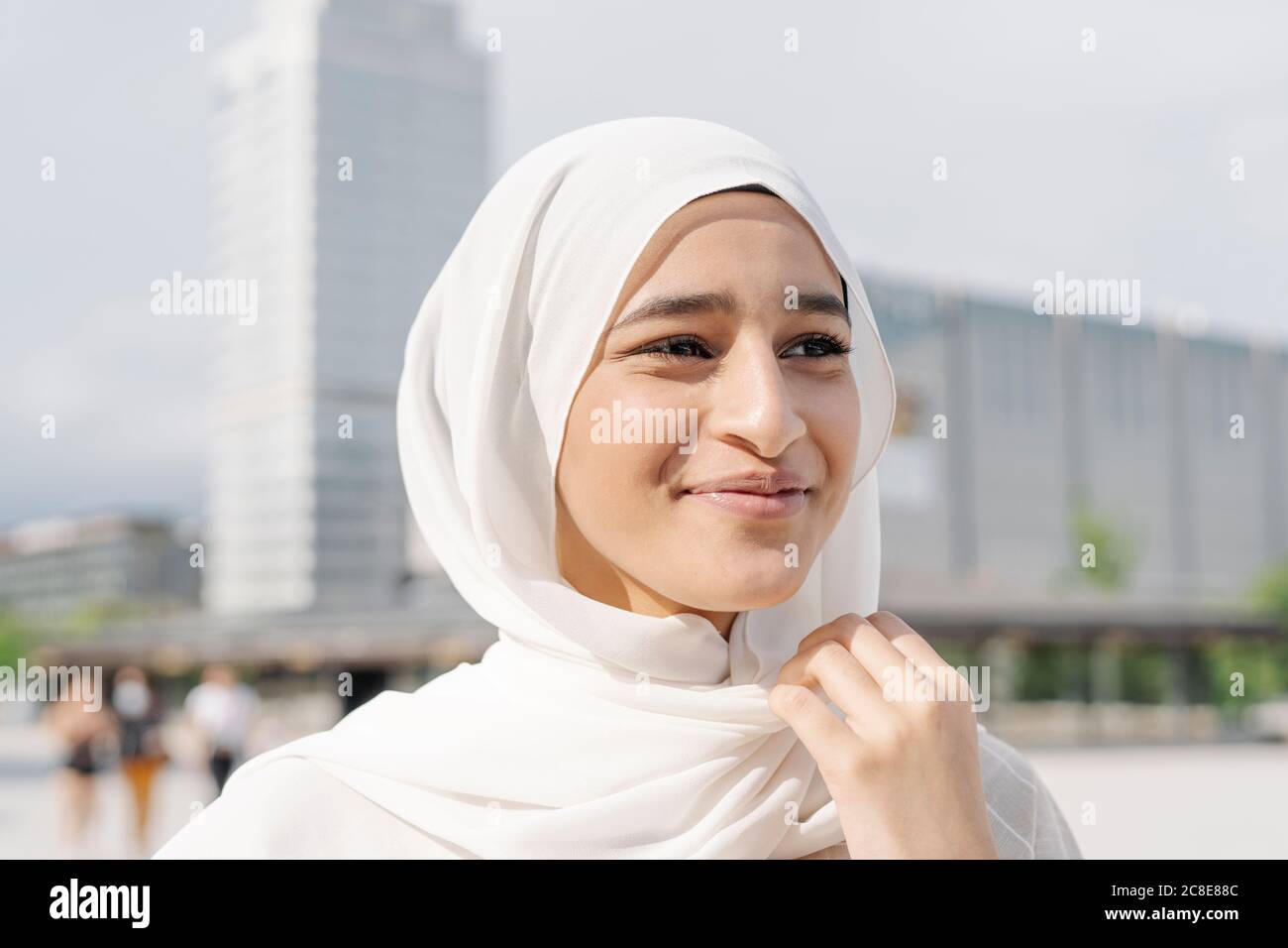 Nachdenkliche Teenager-Mädchen trägt Kopftuch in der Stadt während sonnigen Tag Stockfoto