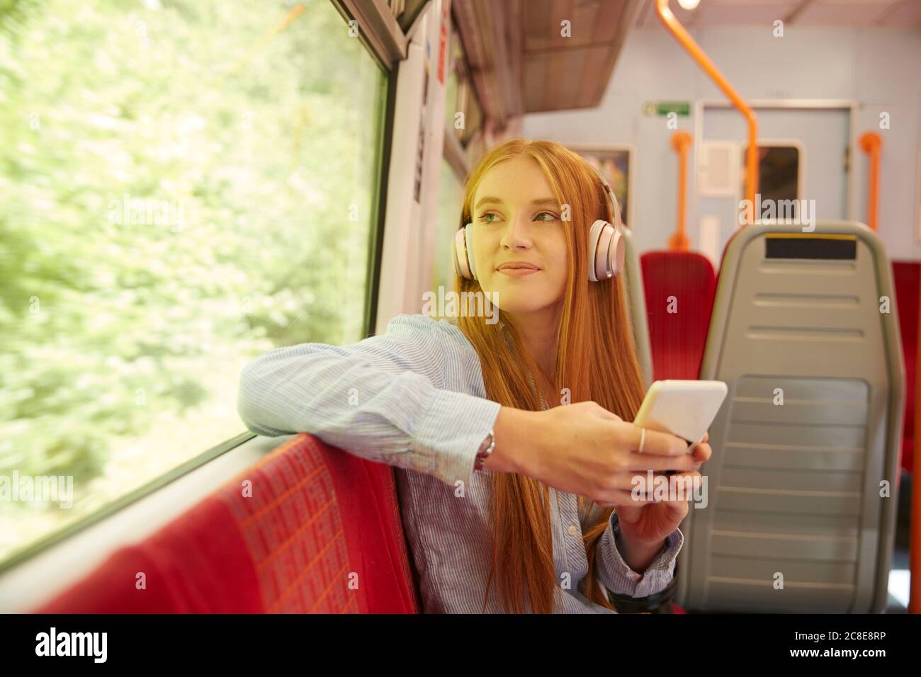 Schöne Frau, die Musik hört, während sie im Zug sitzt Stockfoto