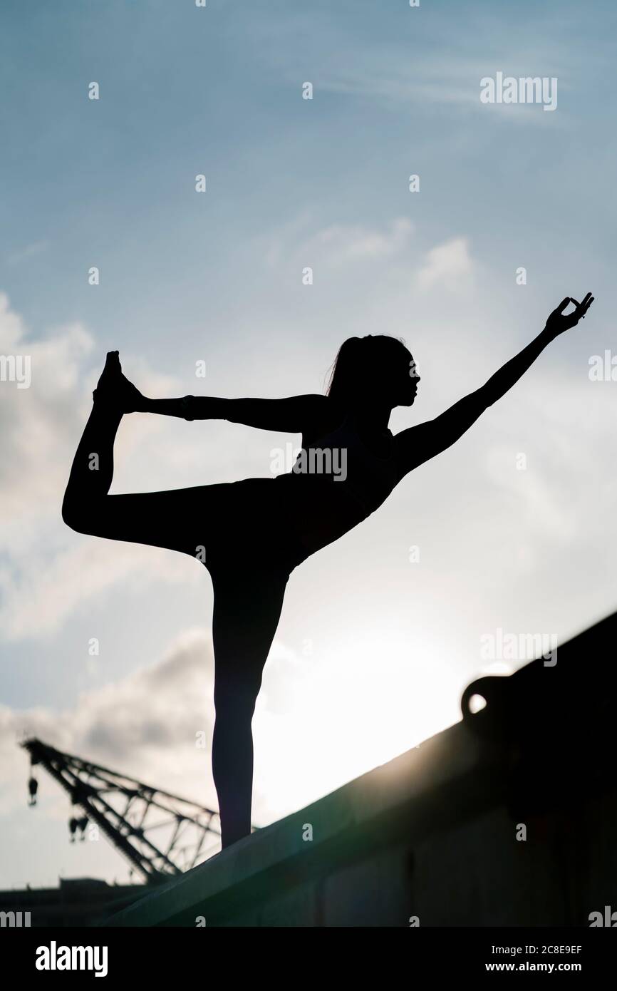 Silhouette Athletin üben Natarajasana auf Pier gegen Himmel Stockfoto