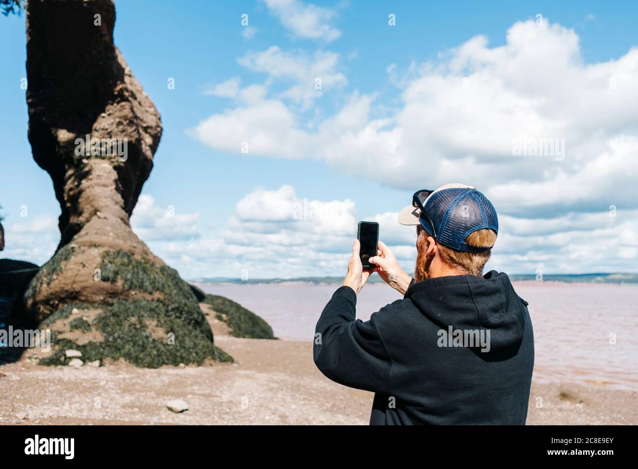 Mann fotografiert Felsformationen im Hopewell Rocks Park, New Brunswick, Kanada Stockfoto