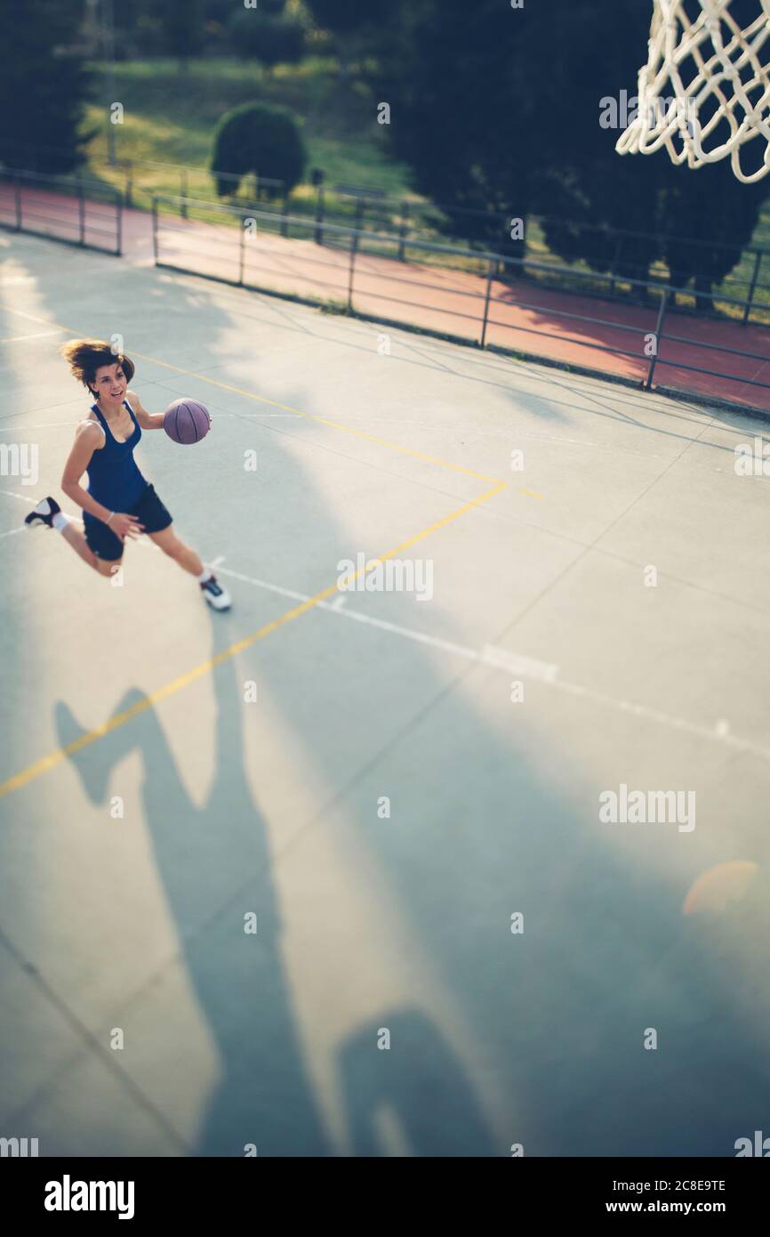 Weibliche Sportlerin beim Laufen mit Basketball beim Training auf dem Platz Stockfoto