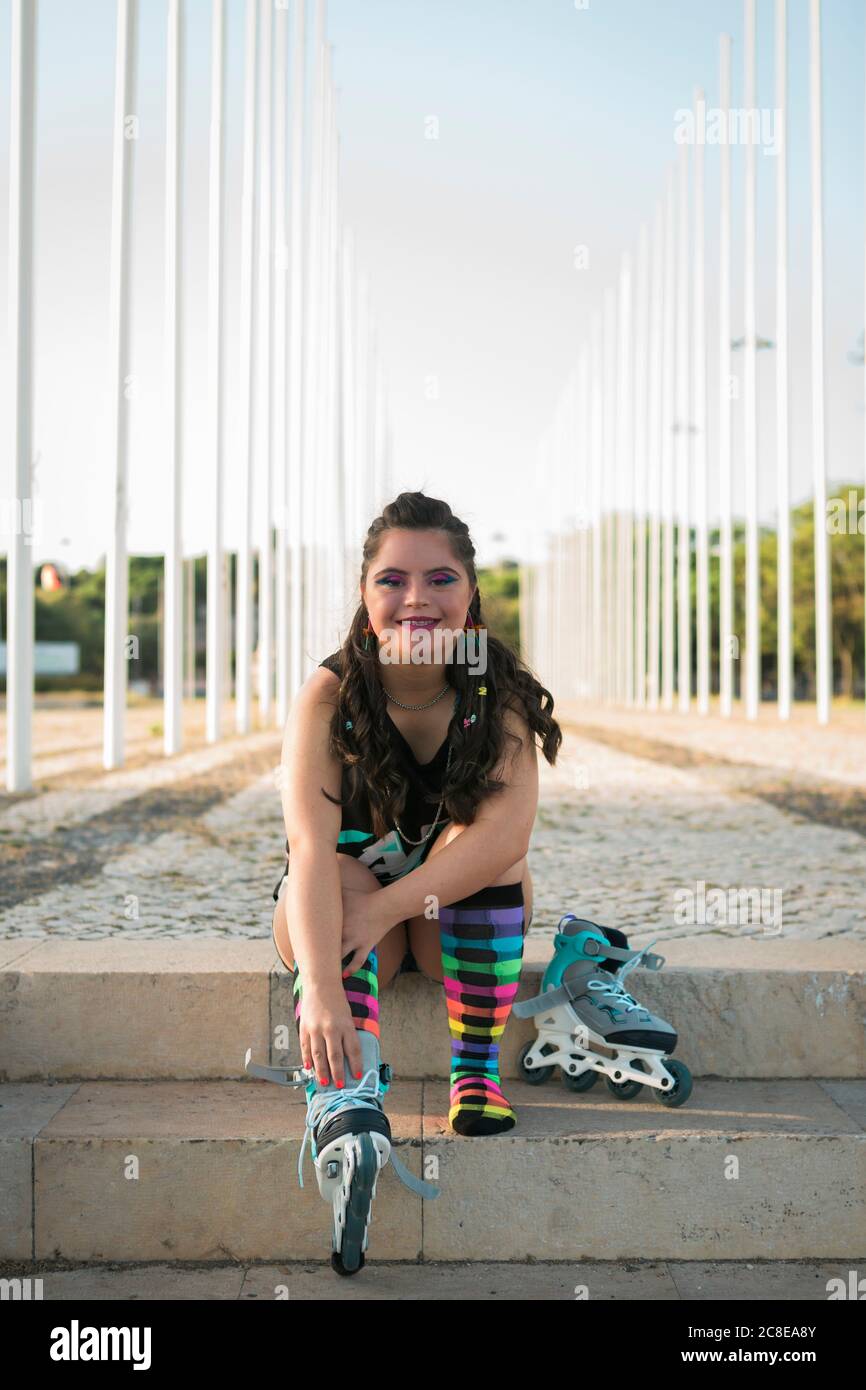 Teenager-Mädchen mit Down-Syndrom trägt 80er Jahre bunte Make-up und Rollschuhe Stockfoto