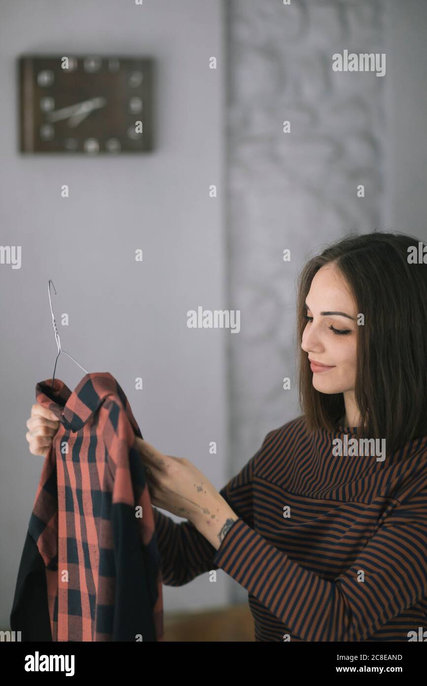 Lächelnde junge Frau, die oben untersucht, während sie im Kleidungsdesign steht studio Stockfoto