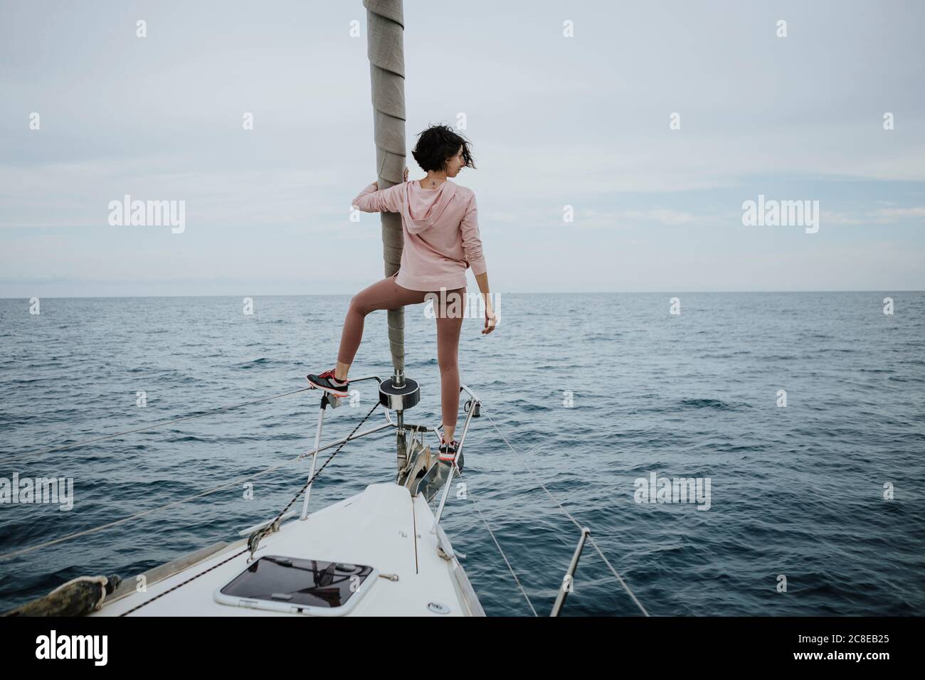 Weibliche Seemannin, die beim Stehen auf dem Bug der Ansicht ist Segelboot im Meer Stockfoto