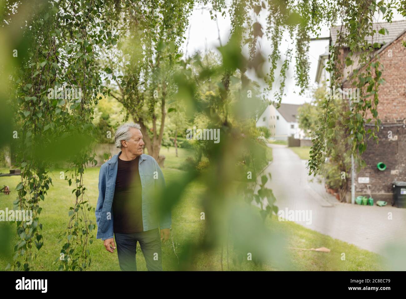 Älterer Mann, der in einem ländlichen Garten steht Stockfoto