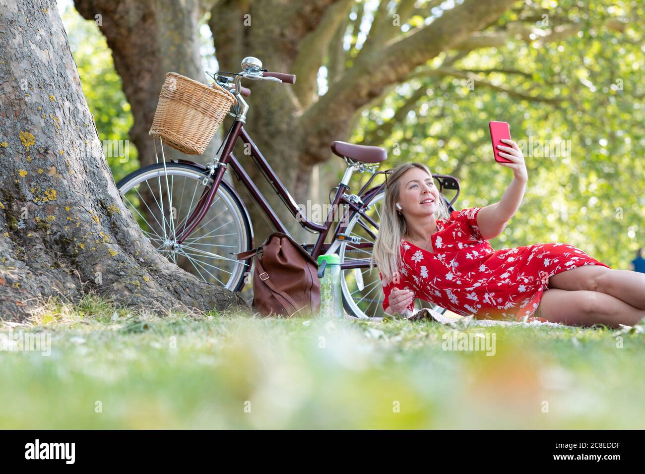 Frau, die Selfie über das Smartphone nimmt, während sie in der Öffentlichkeit liegt parken Stockfoto