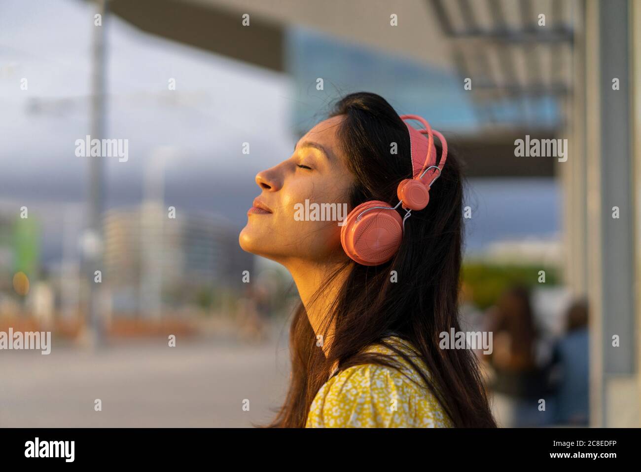 Entspannte junge Frau, die in der Stadt Musik hört Stockfoto