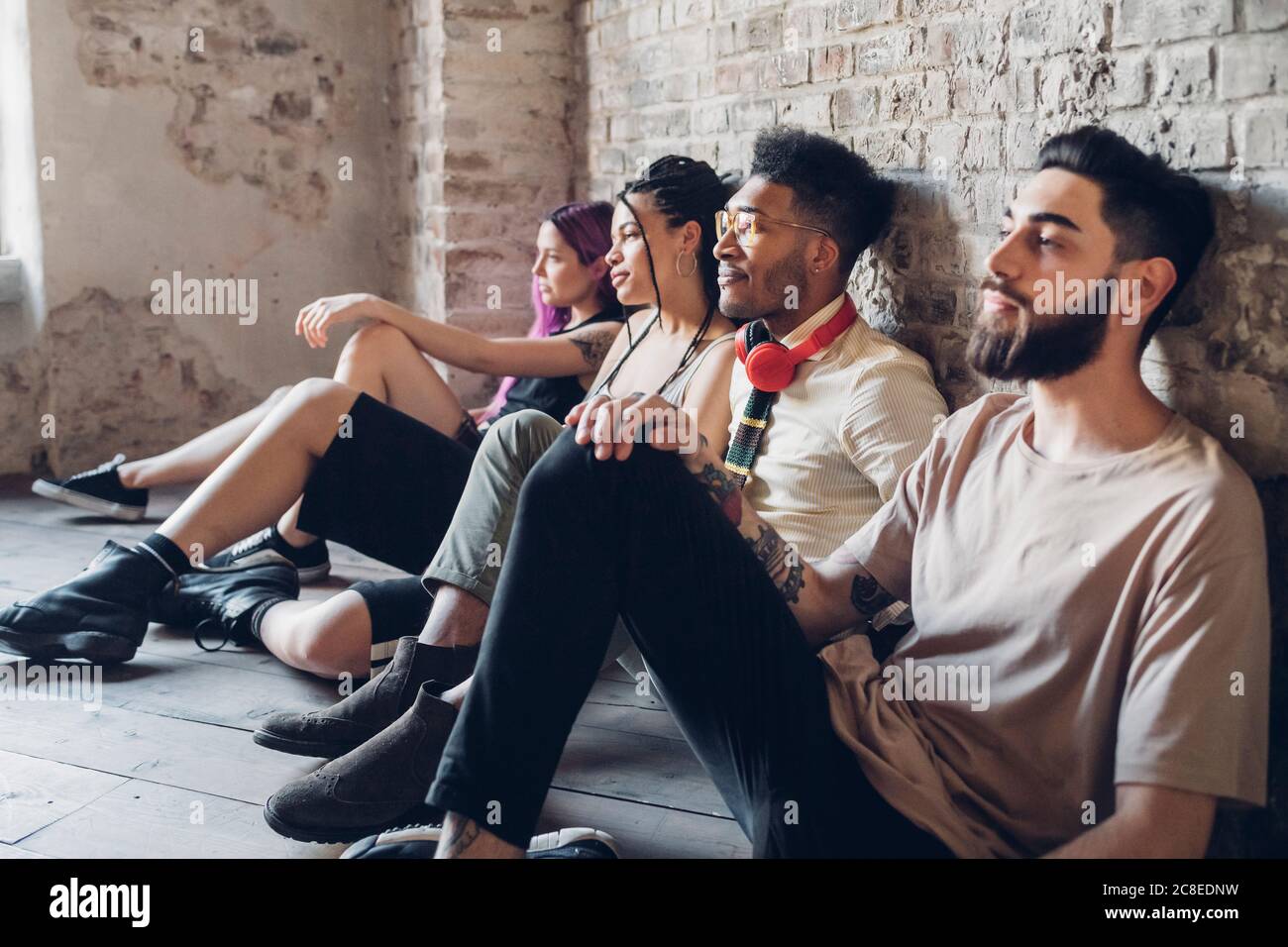 Eine Gruppe von Freunden, die auf dem Boden in einem Loft sitzen Stockfoto