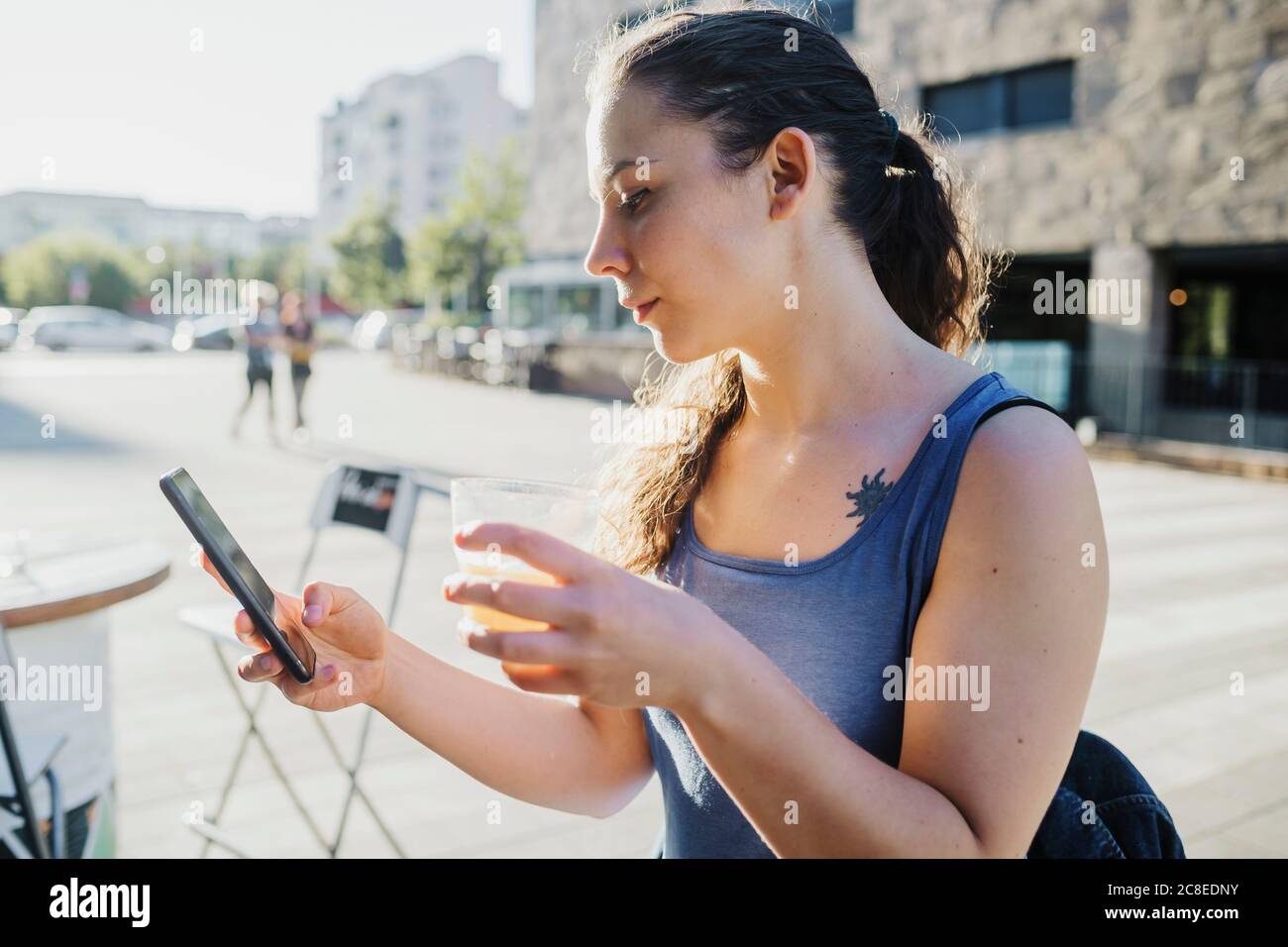 Sportliche junge Frau mit Smartphone, während Sie trinken Straßencafé Stockfoto